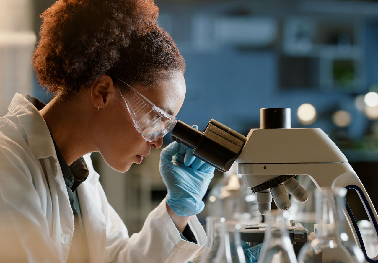 A scientist in a research lab examining samples under a microscope, indicating science-based innovation at Danone.
